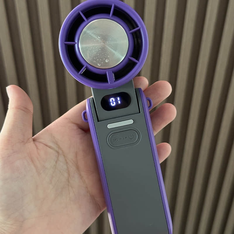 Coolizi portable handheld fan held against wood background