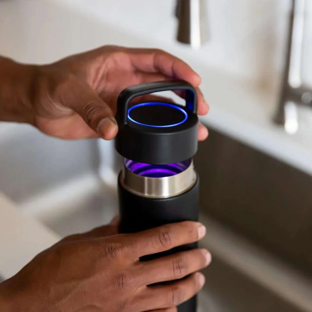 Opening the UV lid on a self-cleaning water bottle in a kitchen