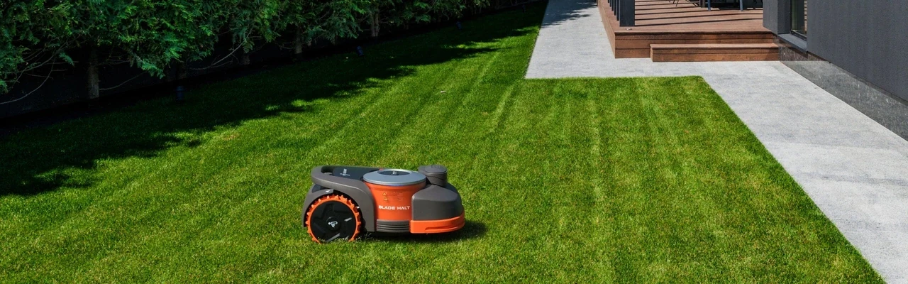 Navimow H-series robot mower with BladeHalt sensor panel on a striped lawn