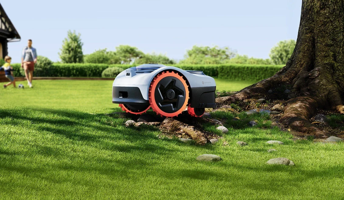 Segway Navimow robot mower climbing tree roots while a family plays on the lawn