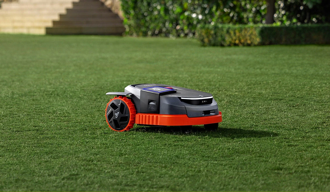 Segway Navimow robot mower with orange bumper on a green lawn