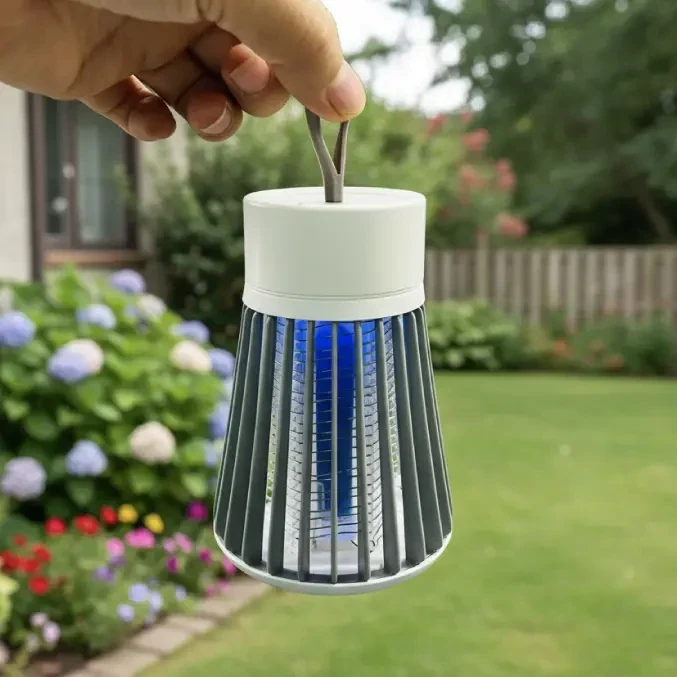 Holding a Qinux NoBuz UV bug zapper outdoors in a garden