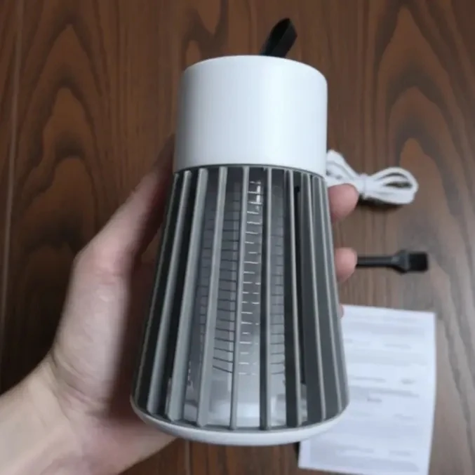 Holding a Qinux NoBuz zapper with USB cable, brush, and manual