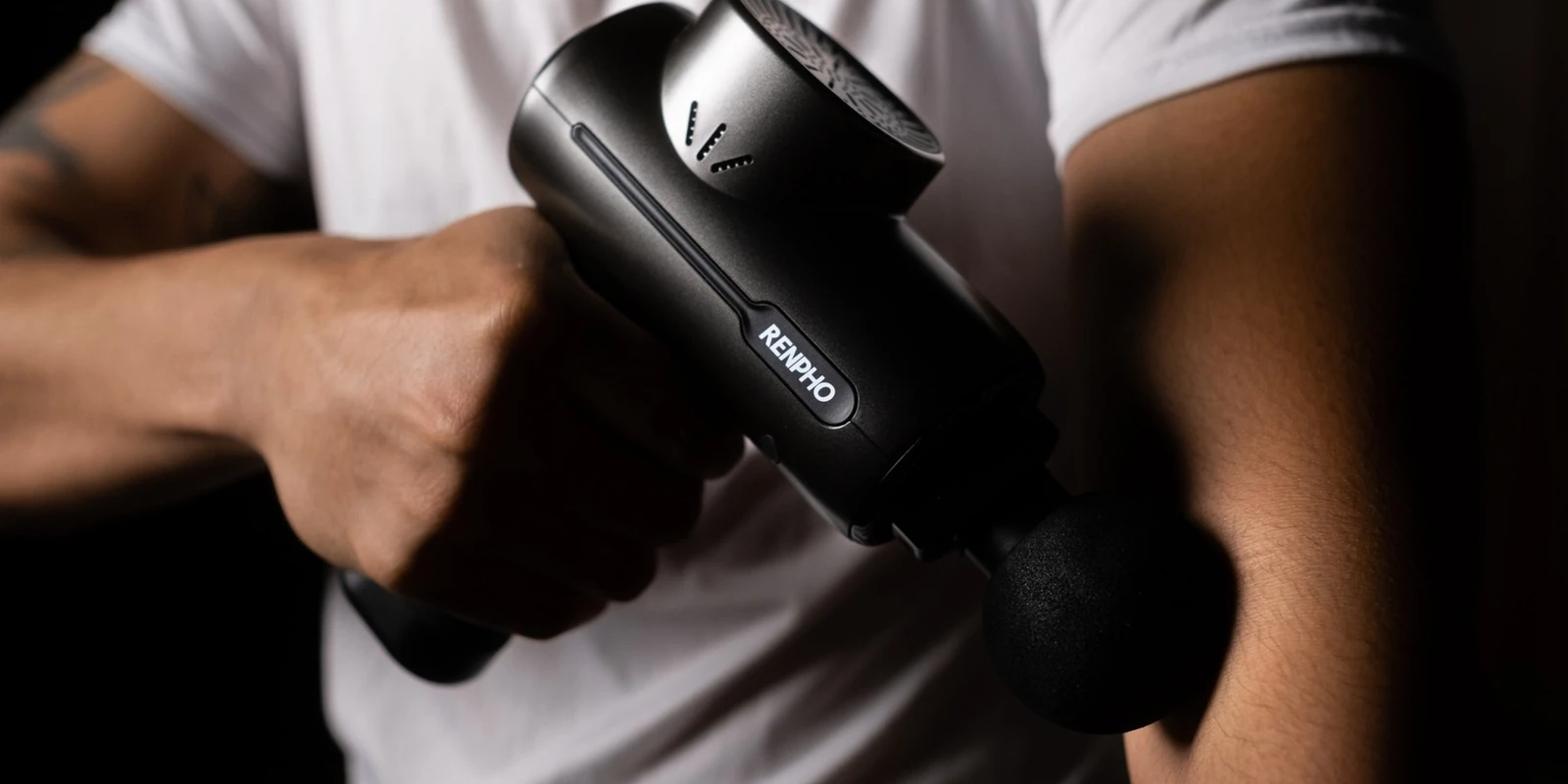 Close-up of a RENPHO massage gun used on the forearm