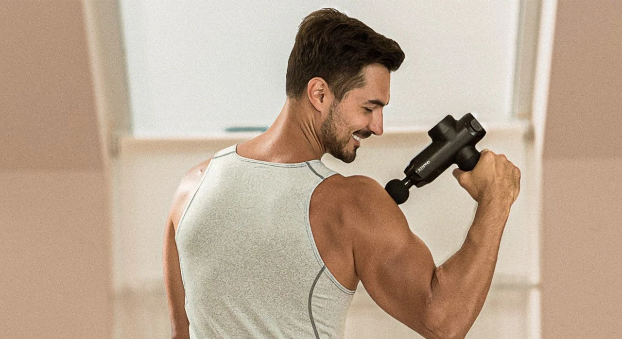Athlete using a RENPHO massage gun on the shoulder after training